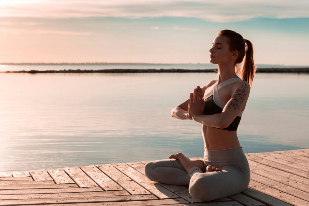 Una mujer en posición de loto practica para aprender a meditar al aire libre