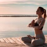 Una mujer en posición de loto practica para aprender a meditar al aire libre