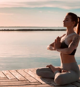 Una mujer en posición de loto practica para aprender a meditar al aire libre