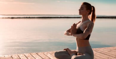 Una mujer en posición de loto practica para aprender a meditar al aire libre