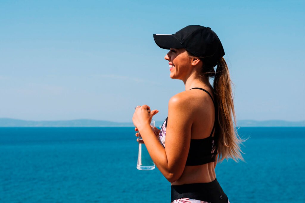 Mujer toma ormus marino junto al mar y está feliz y saludable