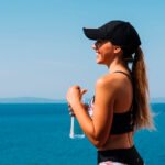 Mujer toma ormus marino junto al mar y está feliz y saludable