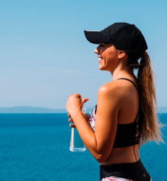 Mujer toma ormus marino junto al mar y está feliz y saludable